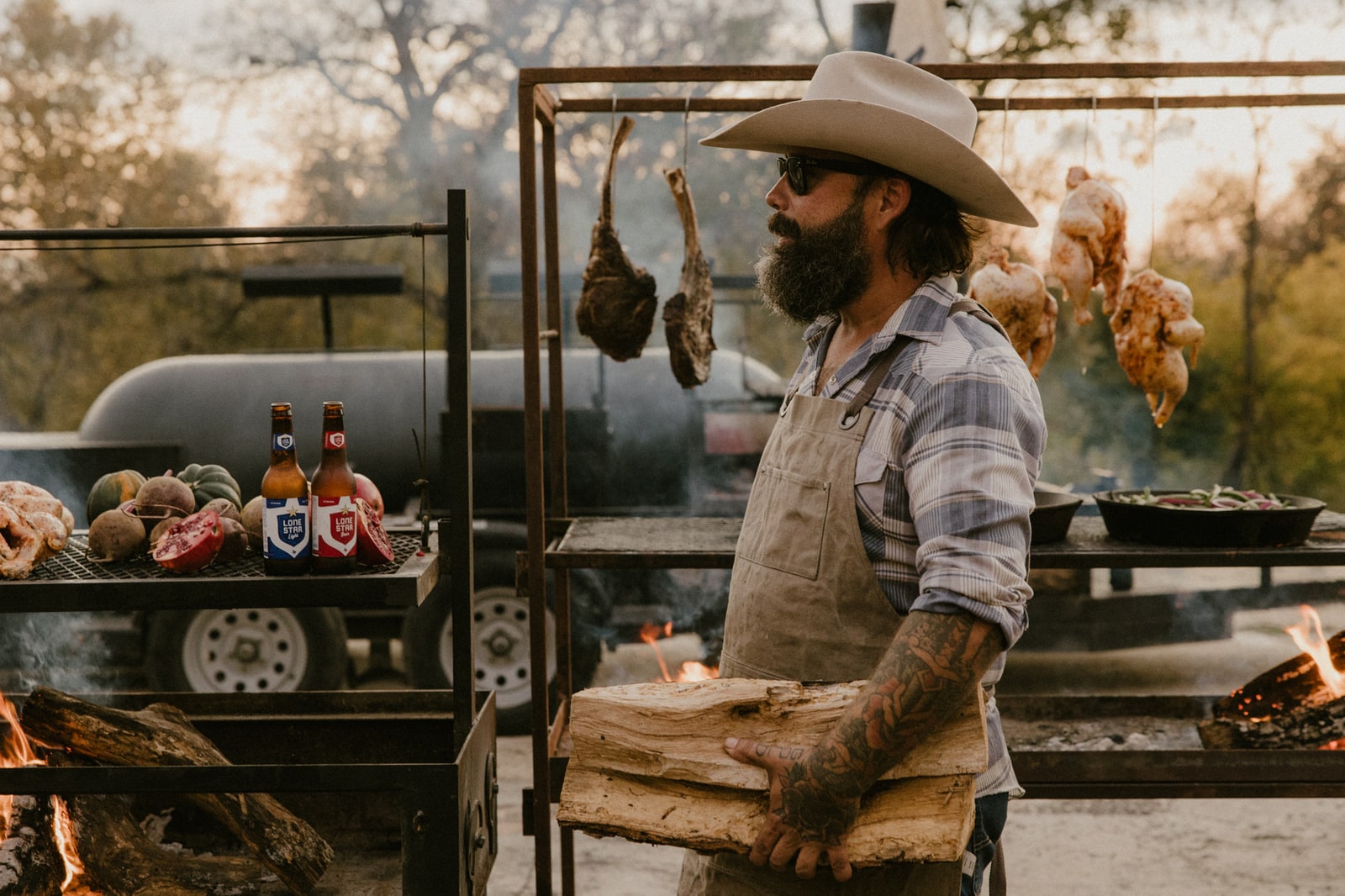 Mike Torres at his live-fire rig, with oak, hanging tomahawks and glowing flames.